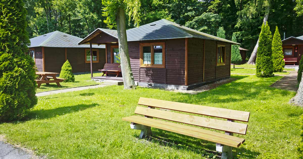Summer camp cabins with picnic tables in a wooded setting available for group rental