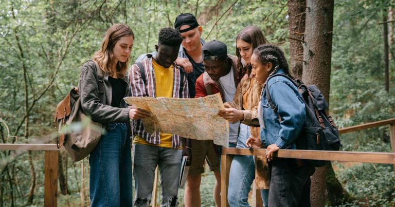 Group of adults reviewing a map outdoors to find a summer camp to rent