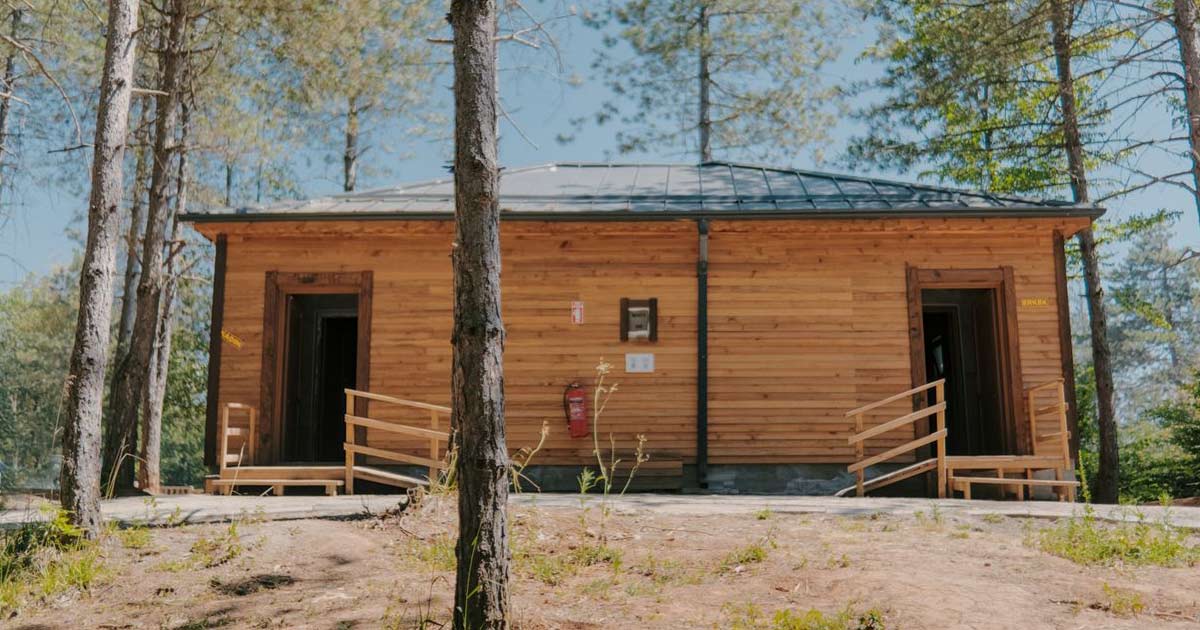 Wooded summer camp bathhouse with a ramp at each entrance